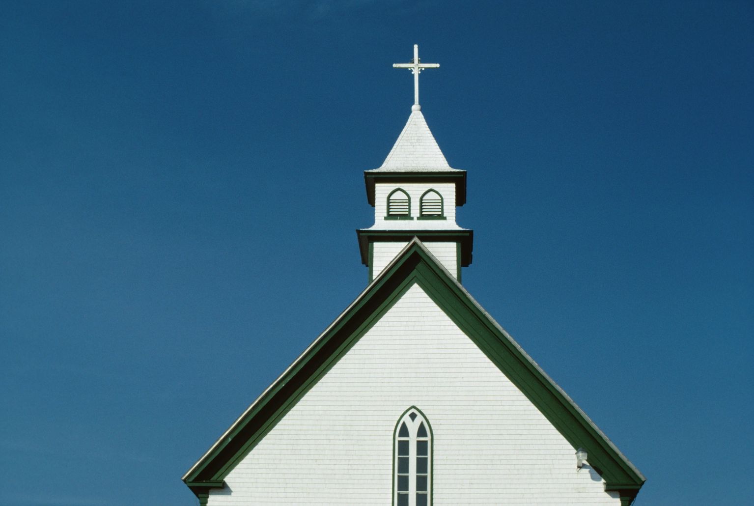White church steeple with cross against blue sky