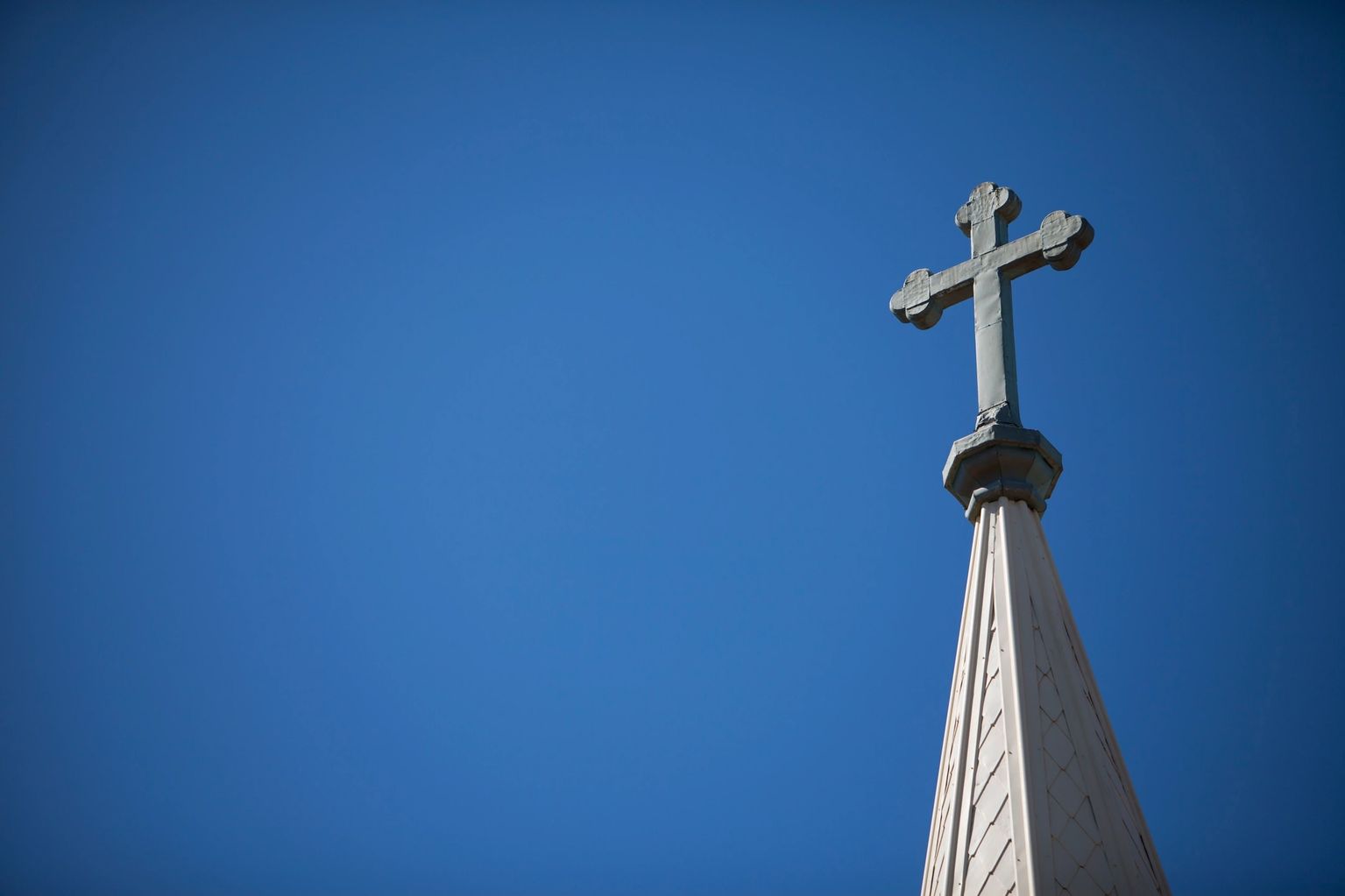 Church steeple cross against clear blue sky