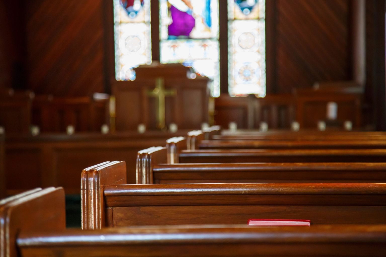 Wooden church pews with stained-glass windows