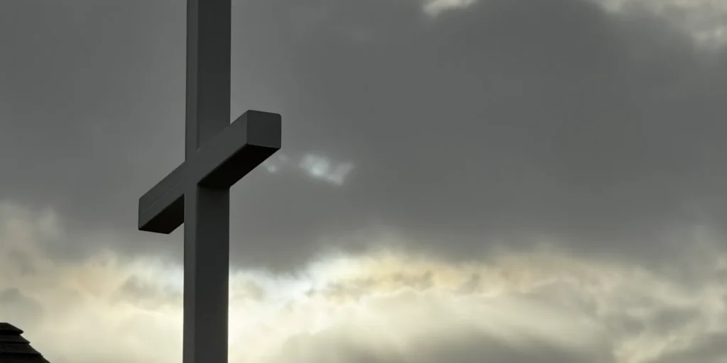 Silhouetted cross against cloudy evening sky