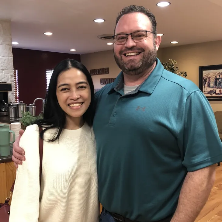 Two smiling people posing inside a living room